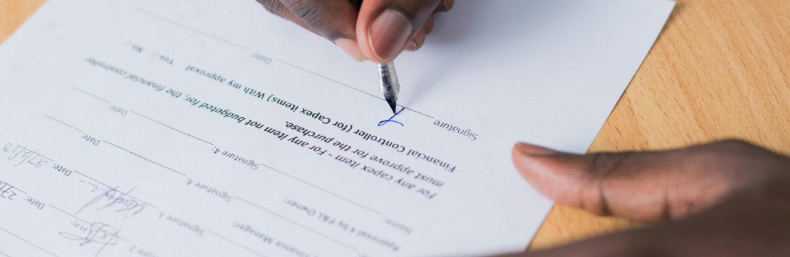 image of a Black man's hands signing paperwork